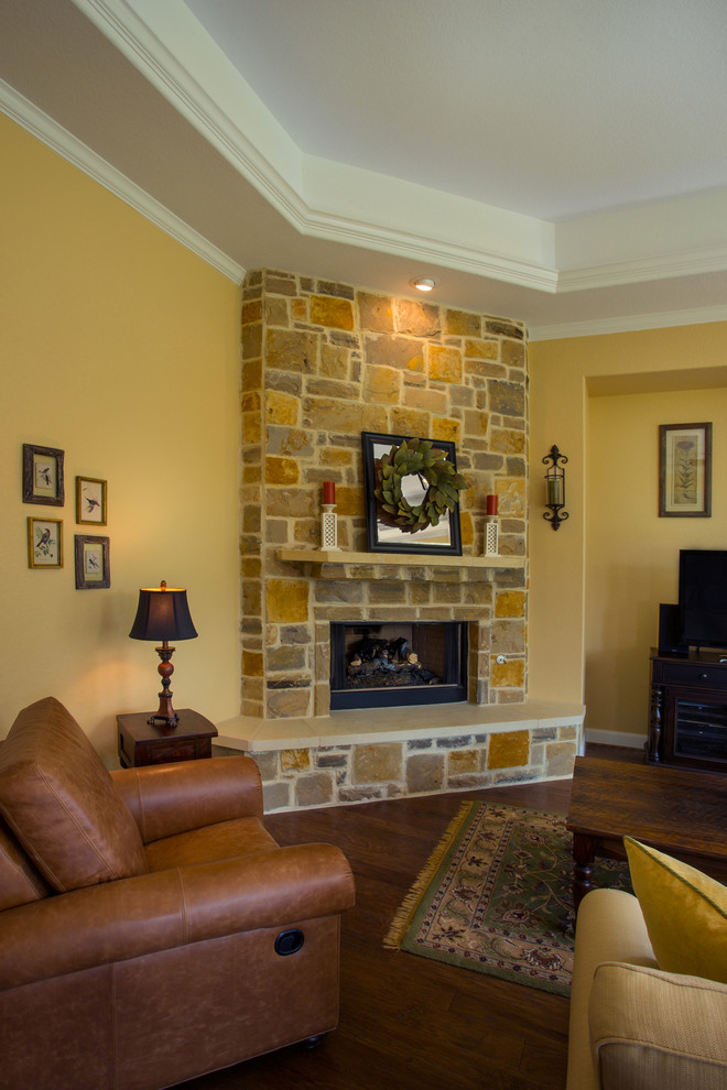 This is an example of a medium sized traditional open plan living room in Austin with yellow walls, medium hardwood flooring, a corner fireplace, a stone fireplace surround and a freestanding tv.
