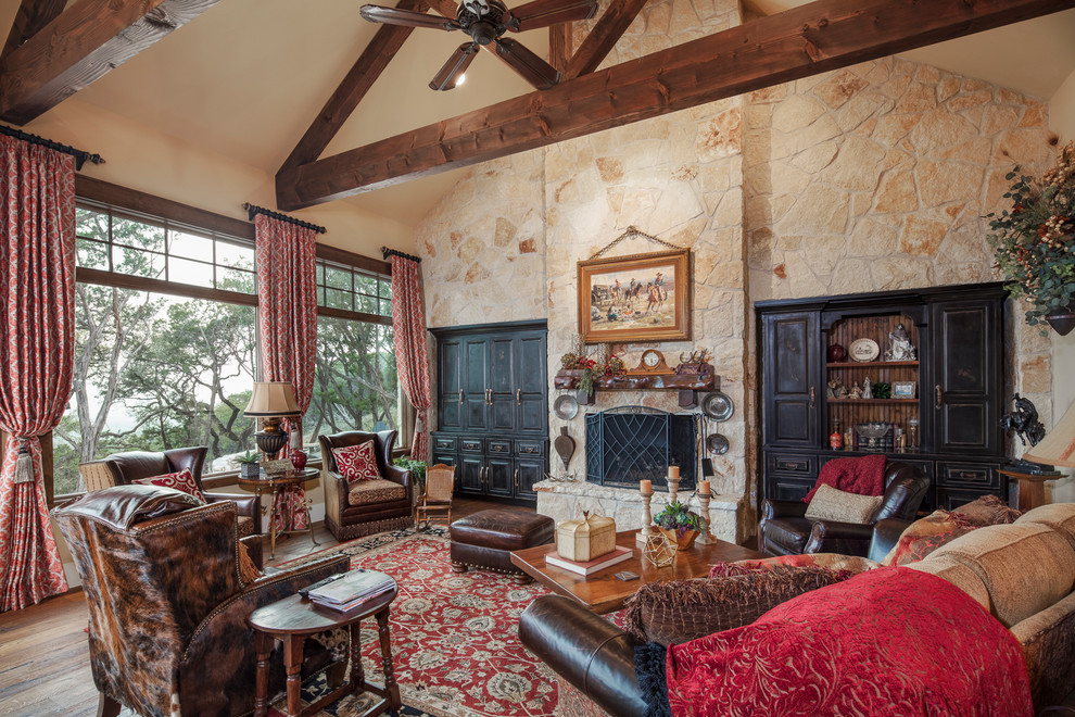 Inspiration for a large rustic open plan living room in Austin with yellow walls, medium hardwood flooring, a standard fireplace, a stone fireplace surround, a concealed tv and brown floors.