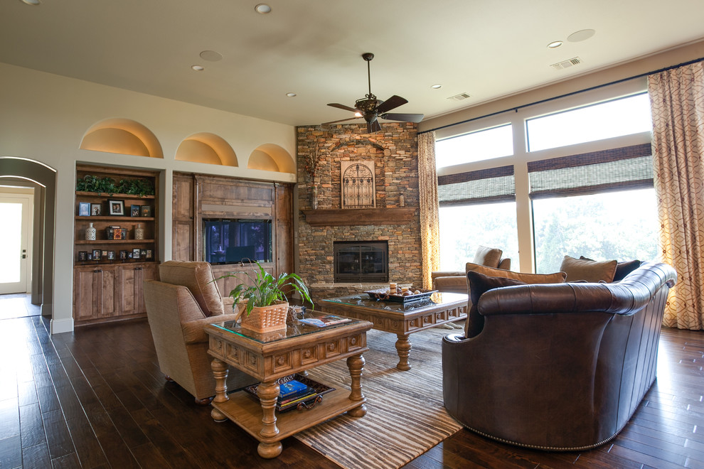 Photo of an expansive mediterranean open plan living room in Dallas with beige walls, dark hardwood flooring, a corner fireplace, a stone fireplace surround and a built-in media unit.