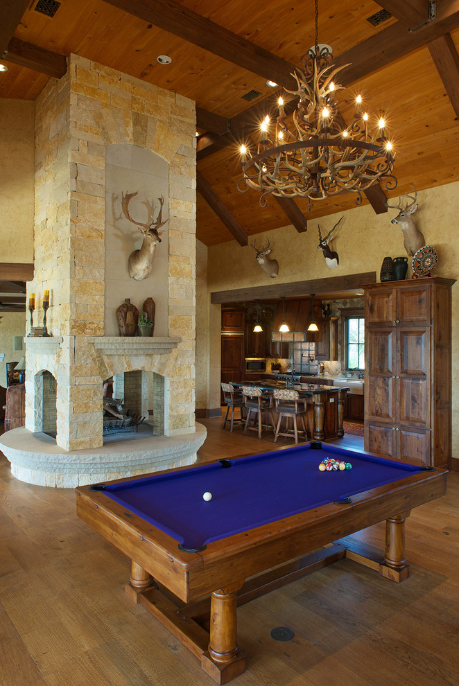 Пример оригинального дизайна: огромная открытая гостиная комната в стиле рустика с бежевыми стенами, светлым паркетным полом, двусторонним камином, фасадом камина из камня и коричневым полом без телевизора