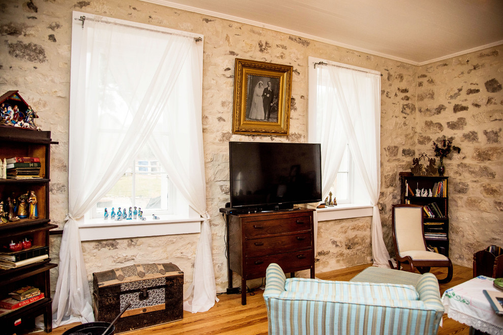Mittelgroßes, Offenes Landhausstil Wohnzimmer mit beiger Wandfarbe, dunklem Holzboden, freistehendem TV und braunem Boden in Austin