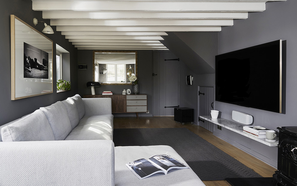 Idéer för att renovera ett mellanstort lantligt separat vardagsrum, med ett musikrum, grå väggar, mellanmörkt trägolv, en öppen vedspis, en spiselkrans i sten, en väggmonterad TV och brunt golv