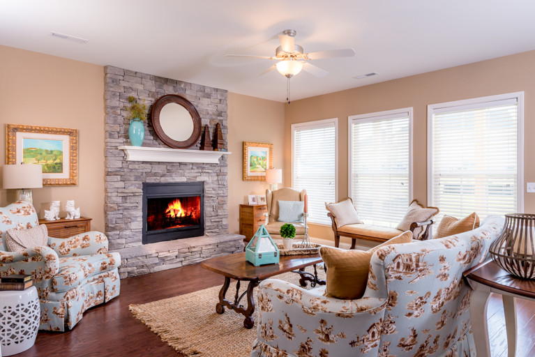 Idée de décoration pour un salon tradition ouvert avec un mur beige, un sol en bois brun, une cheminée standard et un manteau de cheminée en pierre.