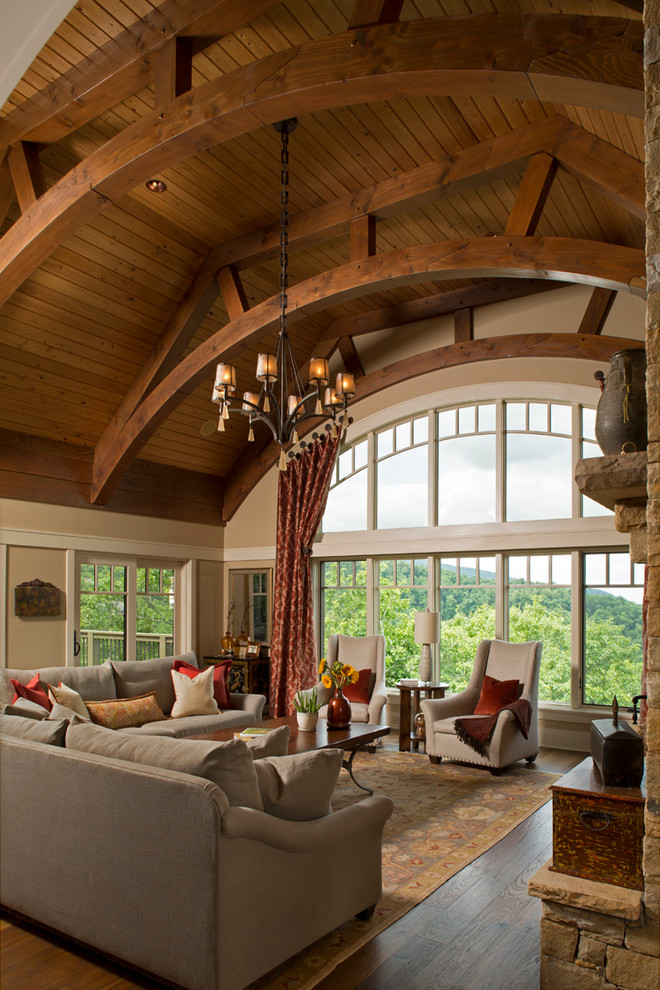Diseño de salón de estilo americano con suelo de madera en tonos medios, todas las chimeneas y marco de chimenea de piedra