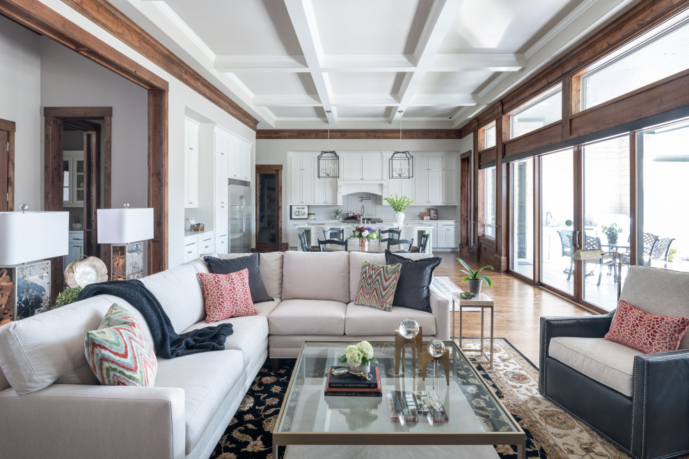 Diseño de salón abierto clásico renovado grande con paredes grises, suelo de madera en tonos medios, suelo marrón, casetón y vigas vistas