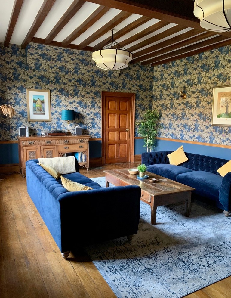 Inredning av ett eklektiskt mycket stort separat vardagsrum, med ett finrum, blå väggar, mörkt trägolv, en standard öppen spis, en spiselkrans i sten och brunt golv
