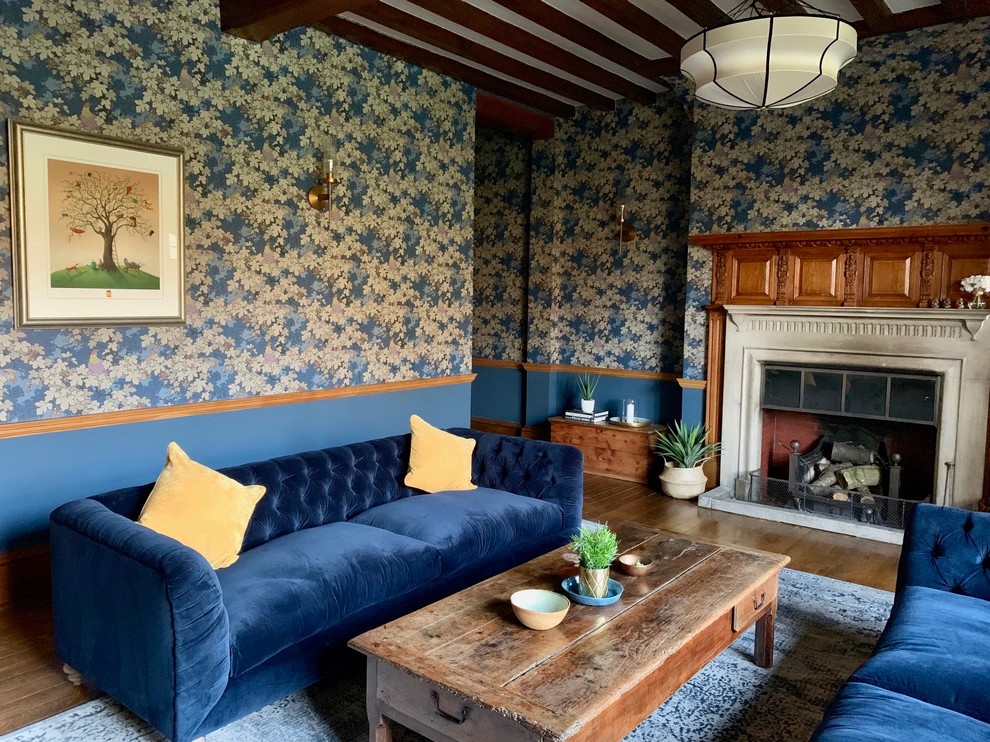 Idée de décoration pour un très grand salon bohème fermé avec une salle de réception, un mur bleu, parquet foncé, une cheminée standard, un manteau de cheminée en pierre, aucun téléviseur et un sol marron.