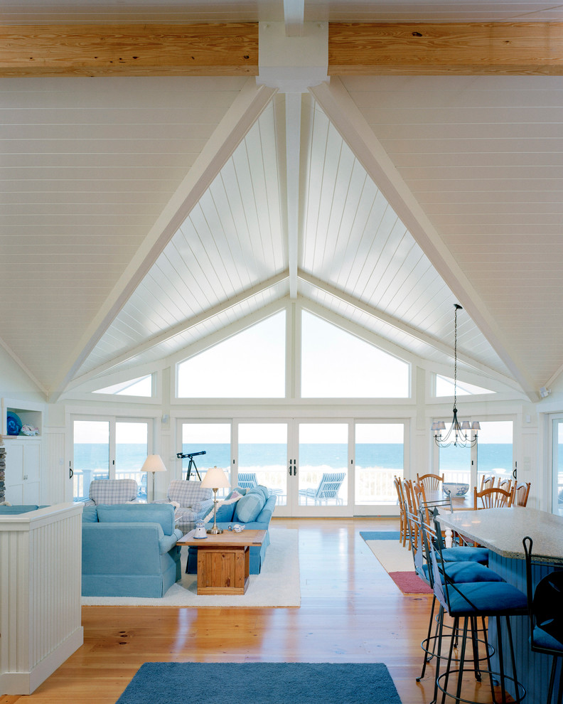 Cette photo montre un grand salon bord de mer ouvert avec un mur blanc, un sol en bois brun et une salle de réception.