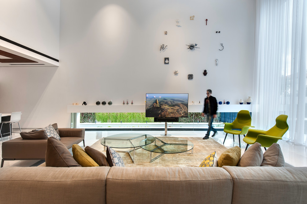 This is an example of a modern open plan living room in Tel Aviv with white walls, a freestanding tv and white floors.