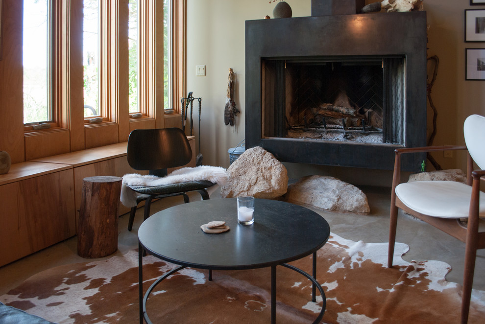 Aménagement d'un grand salon scandinave ouvert avec un mur beige, sol en béton ciré, cheminée suspendue, un manteau de cheminée en plâtre et aucun téléviseur.