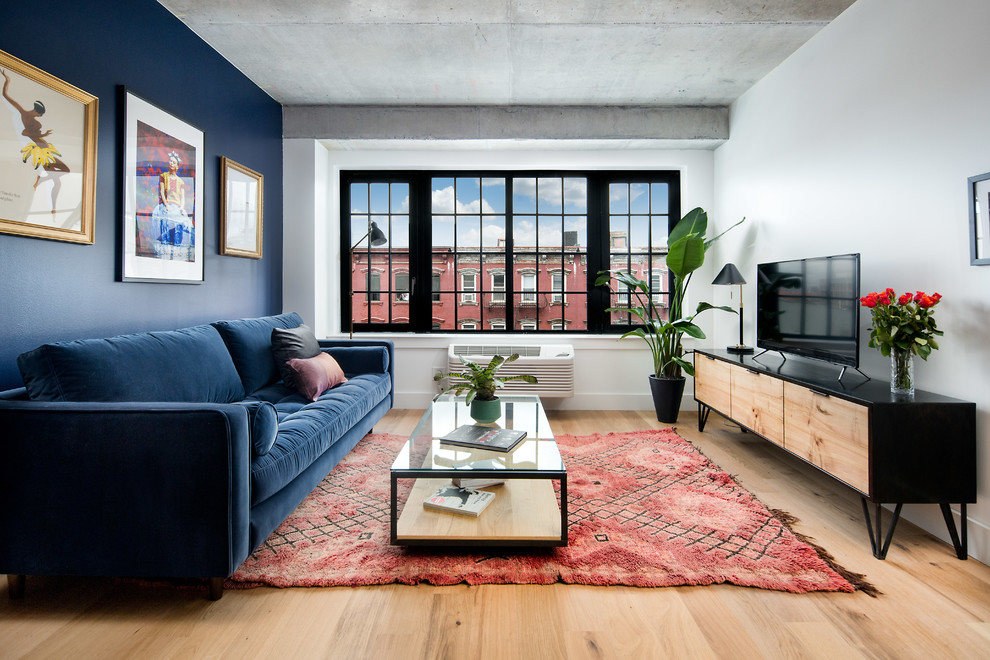 Источник вдохновения для домашнего уюта: изолированная гостиная комната в стиле лофт с разноцветными стенами, паркетным полом среднего тона, отдельно стоящим телевизором, коричневым полом и синим диваном