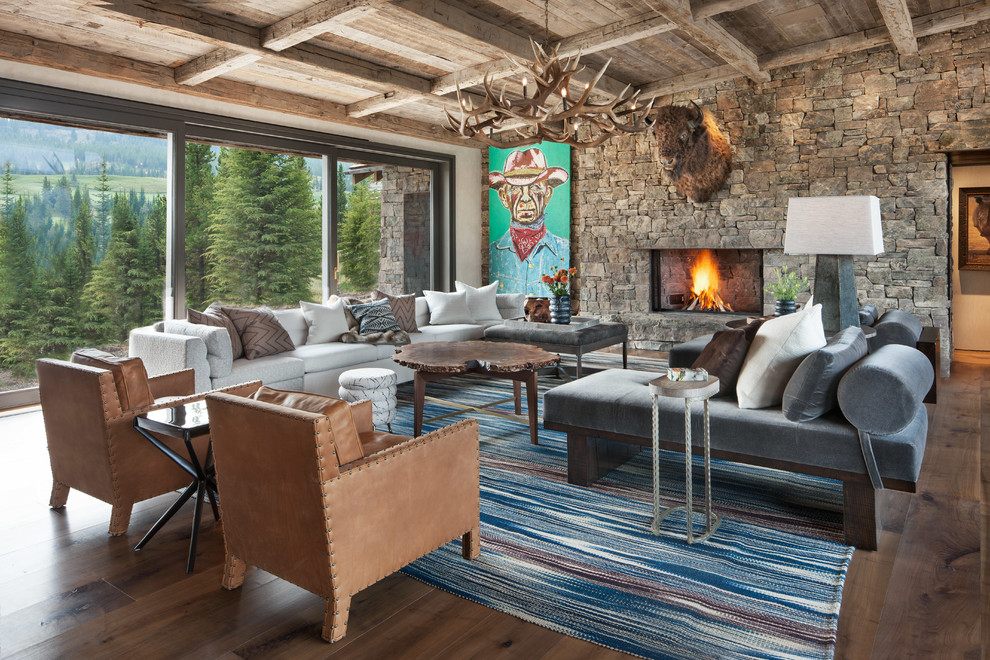 Large rustic open plan living room in Other with medium hardwood flooring, a standard fireplace, a stone fireplace surround, white walls and brown floors.