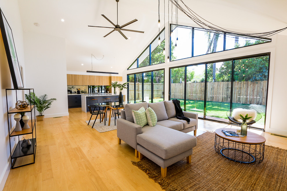 Großes, Offenes Modernes Wohnzimmer mit weißer Wandfarbe, hellem Holzboden und braunem Boden in Brisbane