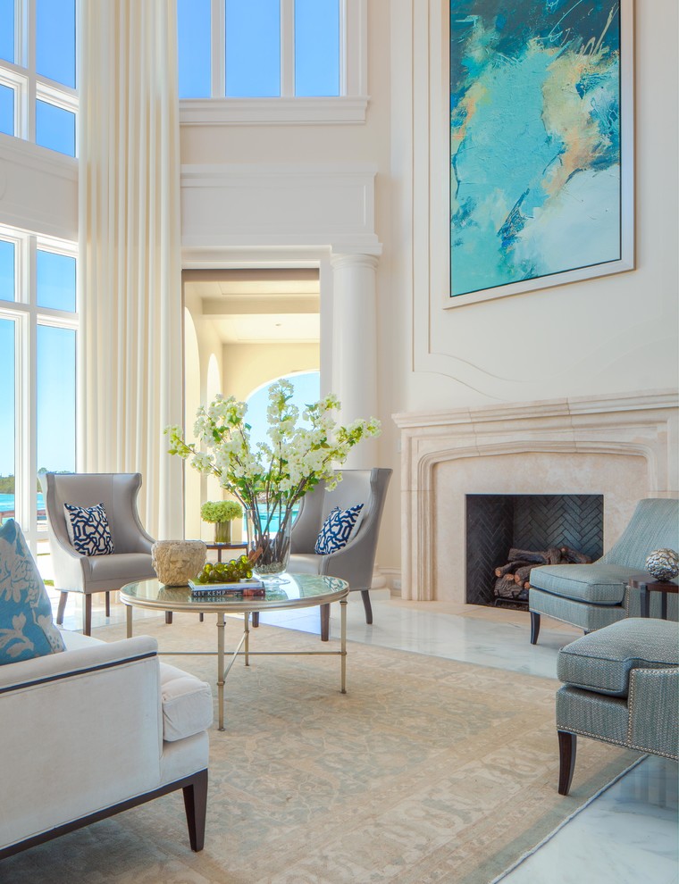 Cette photo montre un grand salon chic ouvert avec une salle de réception, un mur blanc, un sol en marbre, une cheminée standard et un manteau de cheminée en pierre.