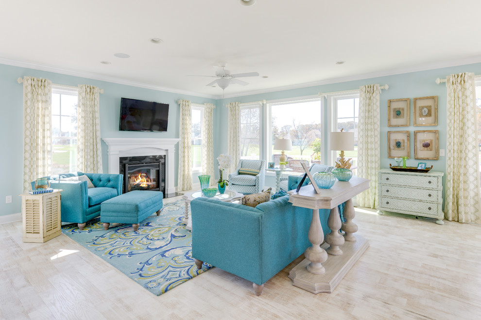 Ejemplo de salón abierto marinero con paredes azules, suelo de madera clara, todas las chimeneas y televisor colgado en la pared