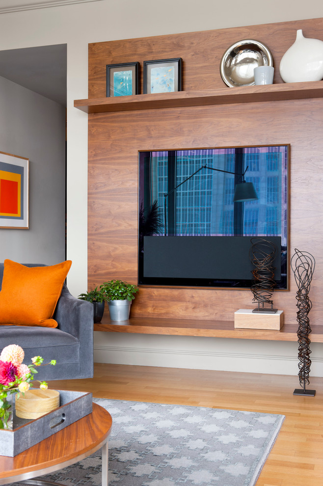 Imagen de salón abierto minimalista de tamaño medio con paredes grises, suelo de madera clara y televisor colgado en la pared