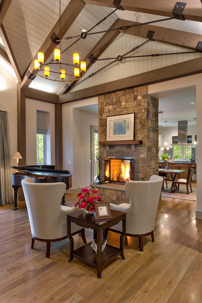 Example of a mid-sized mountain style open concept light wood floor and brown floor living room design in Other with gray walls, a two-sided fireplace, a stone fireplace and a music area