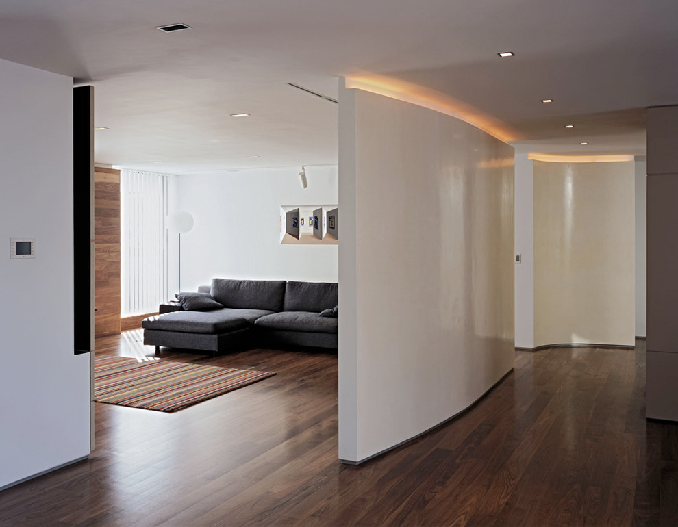 Imagen de salón contemporáneo de tamaño medio con paredes blancas, suelo de madera oscura y televisor colgado en la pared
