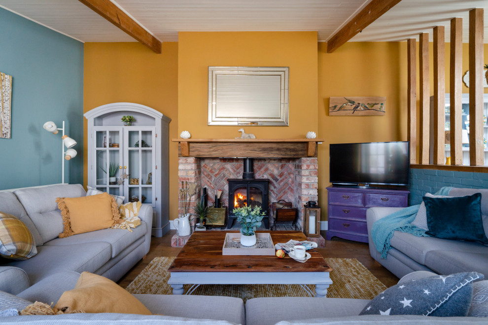 Medium sized traditional formal living room in Devon with yellow walls, medium hardwood flooring, a standard fireplace, a brick fireplace surround, no tv and brown floors.