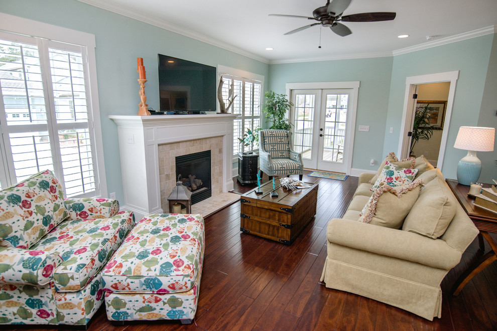 Example of a large beach style dark wood floor living room design in Other with blue walls, a standard fireplace, a tile fireplace and a wall-mounted tv