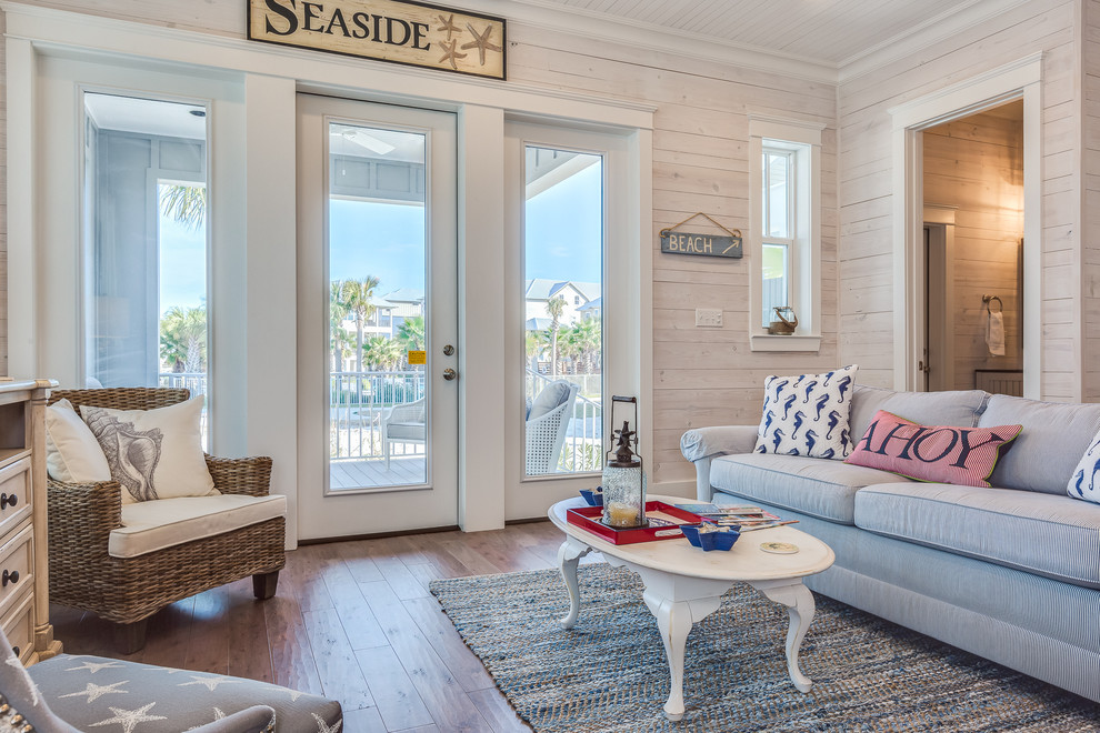 Пример оригинального дизайна: гостиная комната в морском стиле с паркетным полом среднего тона и синим диваном