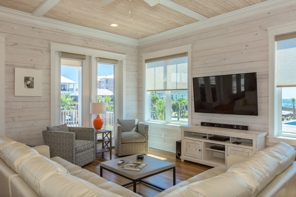 Immagine di un soggiorno costiero con pavimento in legno massello medio e TV a parete