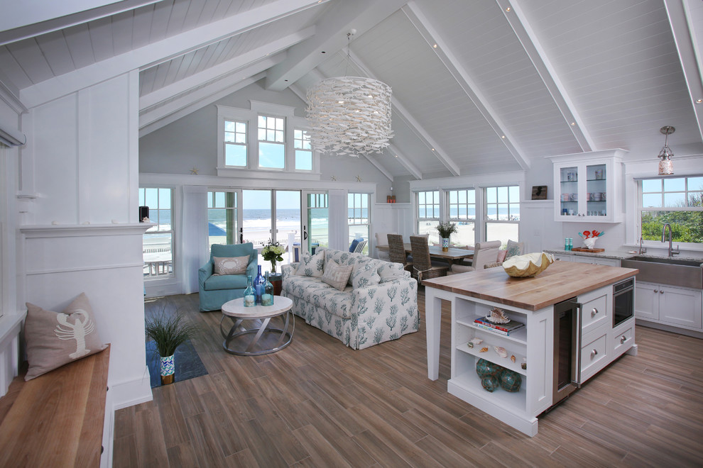 Immagine di un grande soggiorno stile marino aperto con pareti bianche, pavimento in legno massello medio e pavimento marrone