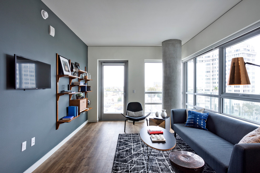 Idee per un soggiorno contemporaneo con pareti grigie, pavimento in legno massello medio e TV a parete