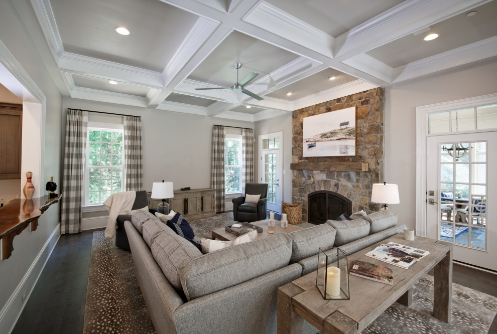 Large traditional enclosed living room in DC Metro with a home bar, a stone fireplace surround, a coffered ceiling, no tv, dark hardwood flooring, a standard fireplace, multi-coloured floors and wainscoting.