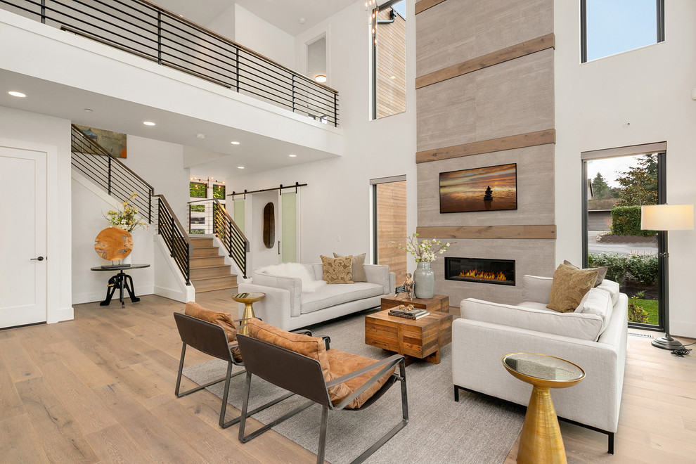 Cette photo montre un grand salon tendance ouvert avec un mur blanc, un sol en bois brun, une cheminée standard, un manteau de cheminée en métal, un téléviseur fixé au mur, un sol gris et éclairage.