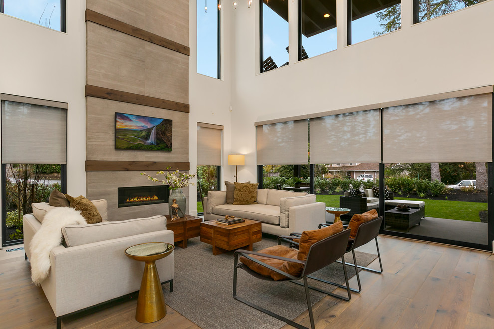 Großes, Offenes Modernes Wohnzimmer mit weißer Wandfarbe, braunem Holzboden, Kamin, gefliester Kaminumrandung, TV-Wand und grauem Boden in Seattle