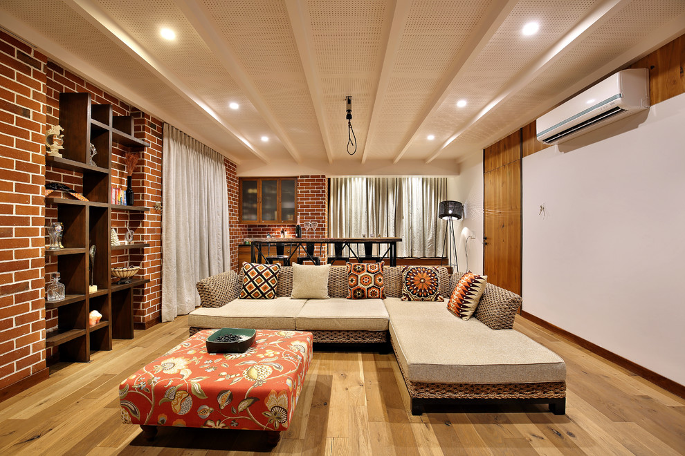 Mid-sized open concept medium tone wood floor living room photo in Ahmedabad