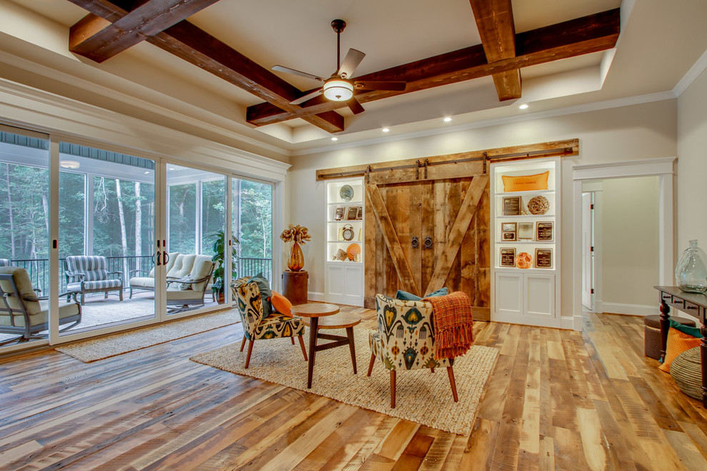 Imagen de salón para visitas campestre grande con suelo de madera clara y televisor retractable