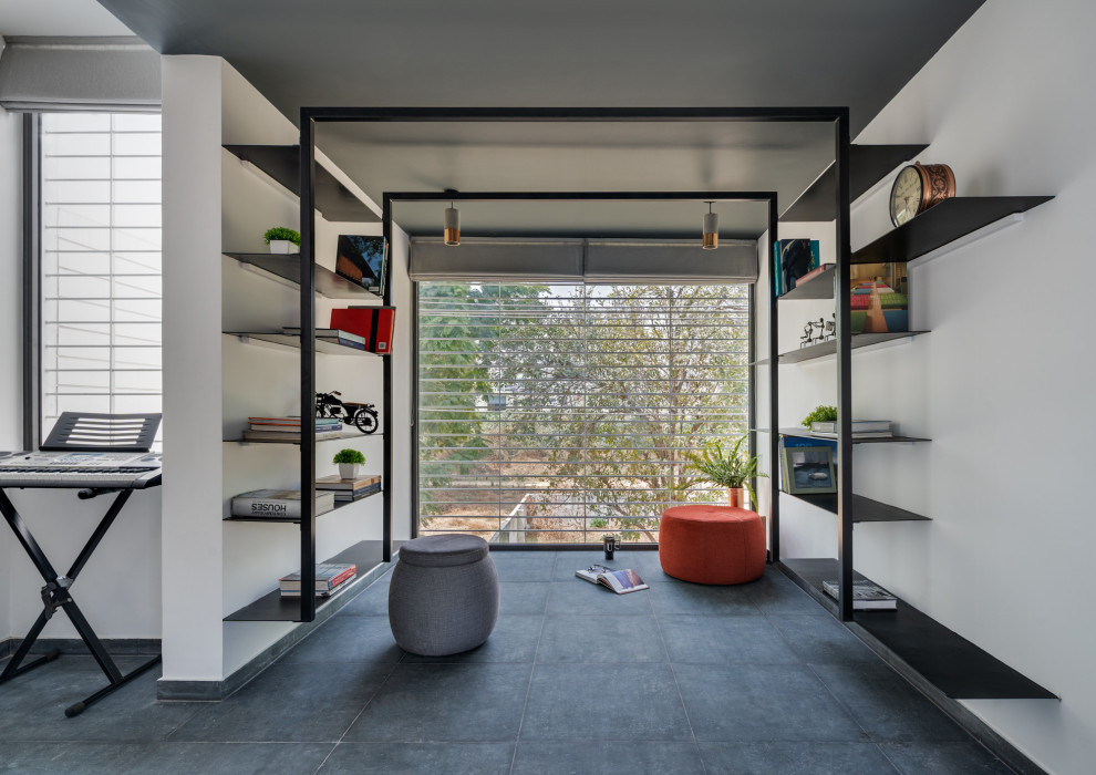 Cette photo montre une salle de séjour tendance de taille moyenne et ouverte avec une bibliothèque ou un coin lecture, un mur blanc, aucun téléviseur et un sol gris.