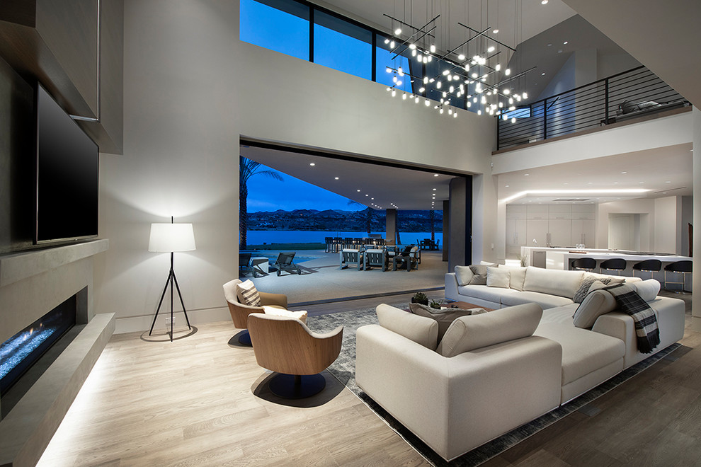 Example of a huge trendy formal and open concept light wood floor and gray floor living room design in Las Vegas with gray walls, a standard fireplace, a concrete fireplace and a media wall