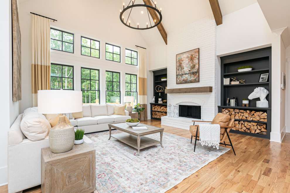 Large classic open plan living room in Atlanta with white walls, medium hardwood flooring, a standard fireplace, a brick fireplace surround, no tv, brown floors and a vaulted ceiling.