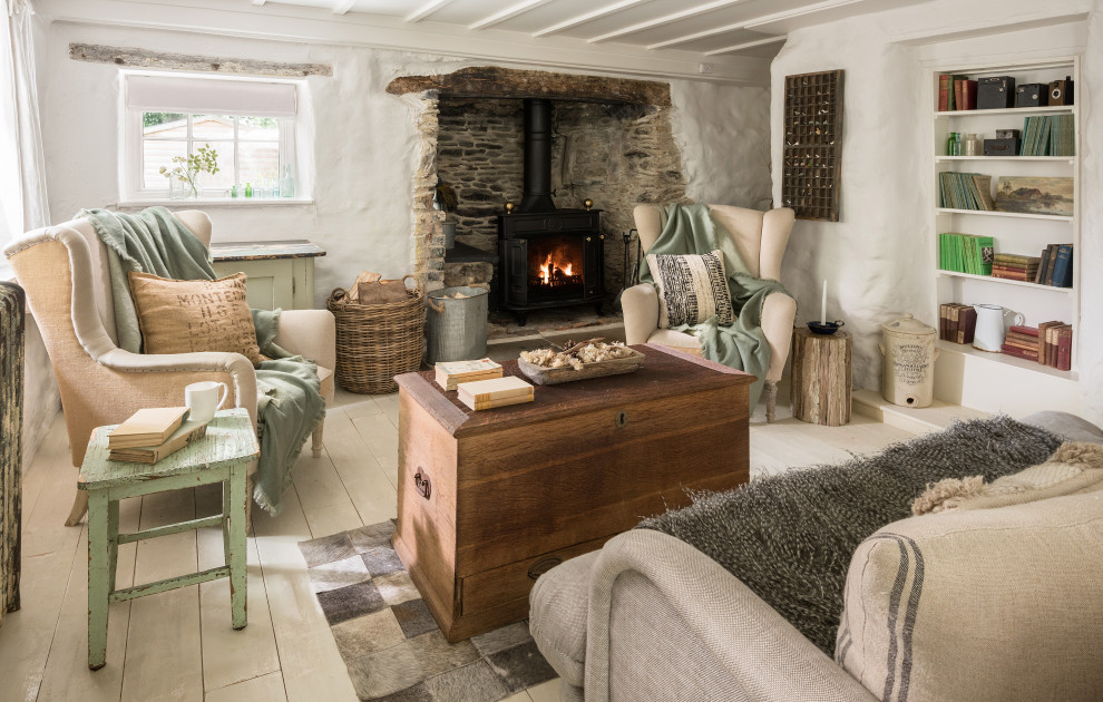 Mid-sized cottage chic painted wood floor and white floor living room photo in Cornwall with white walls, a standard fireplace and a stone fireplace