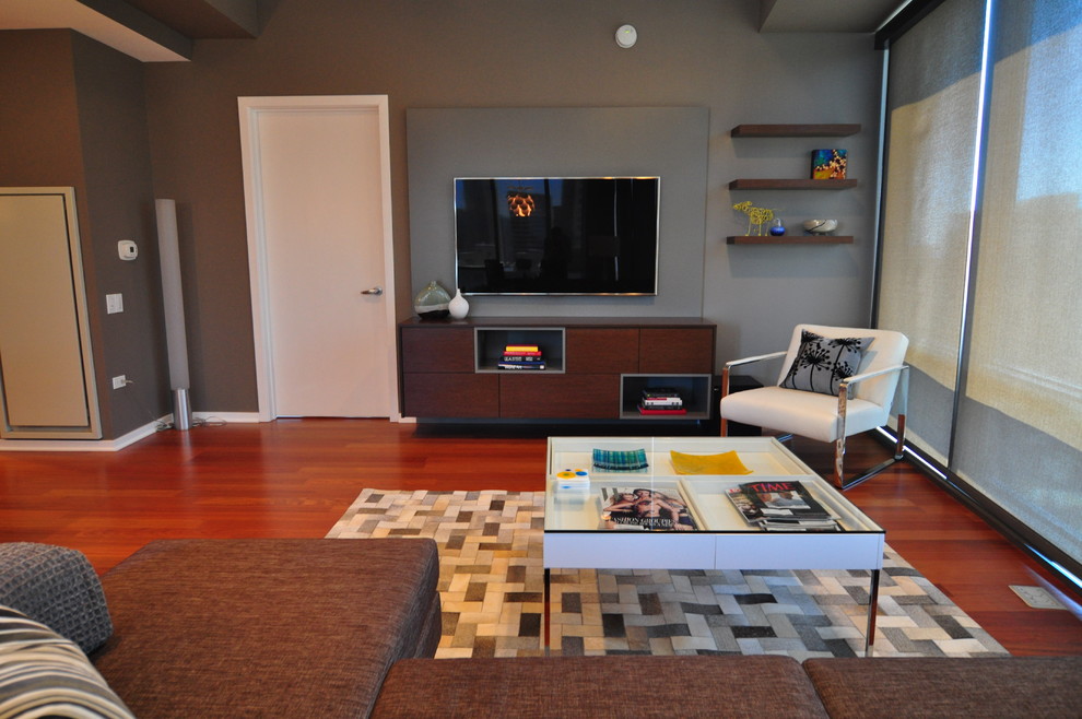 Foto de salón abierto contemporáneo grande con paredes grises, suelo de madera en tonos medios y televisor colgado en la pared