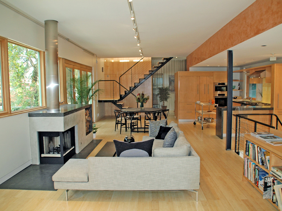Diseño de salón abierto actual de tamaño medio con chimenea de doble cara, paredes blancas, suelo de madera clara y marco de chimenea de yeso