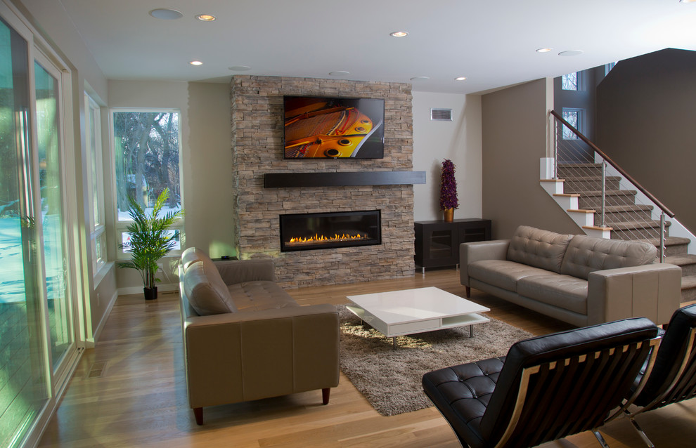 This is an example of a medium sized contemporary formal open plan living room in Milwaukee with grey walls, light hardwood flooring, a ribbon fireplace, a stone fireplace surround and a wall mounted tv.