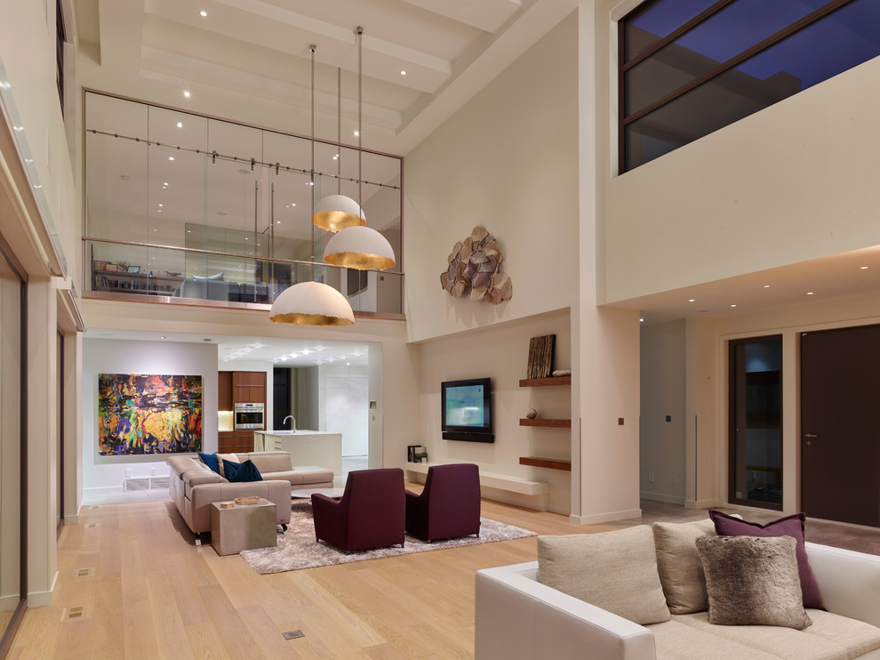 Large modern open plan living room in Edmonton with white walls, light hardwood flooring and beige floors.