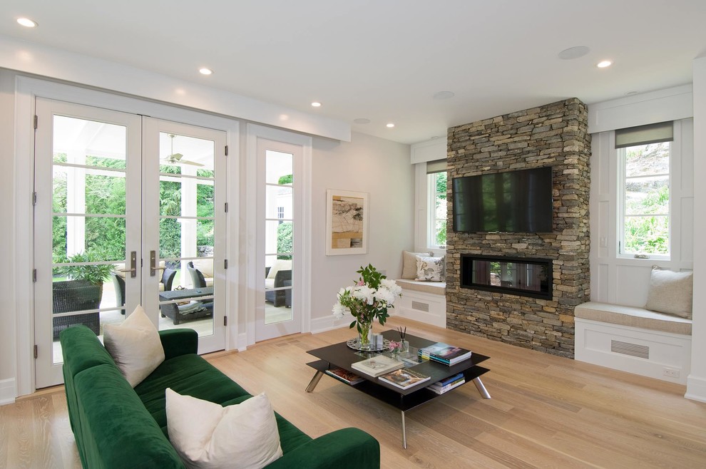 Photo of a large traditional open plan living room in New York with white walls, light hardwood flooring, a standard fireplace, a stone fireplace surround and a wall mounted tv.