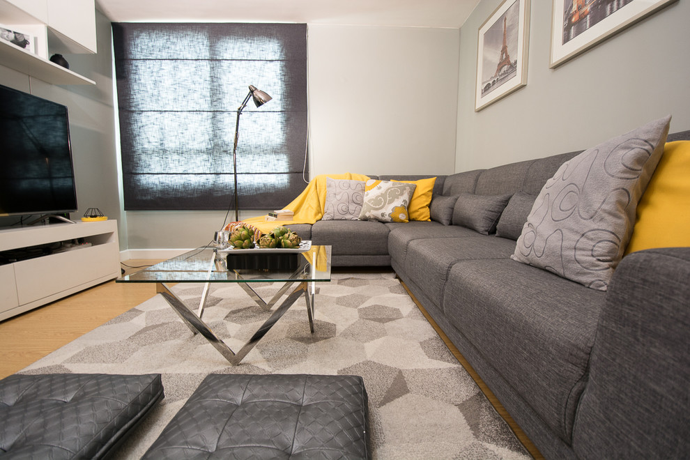 На фото: маленькая изолированная гостиная комната в современном стиле с серыми стенами, полом из ламината и телевизором на стене без камина для на участке и в саду с