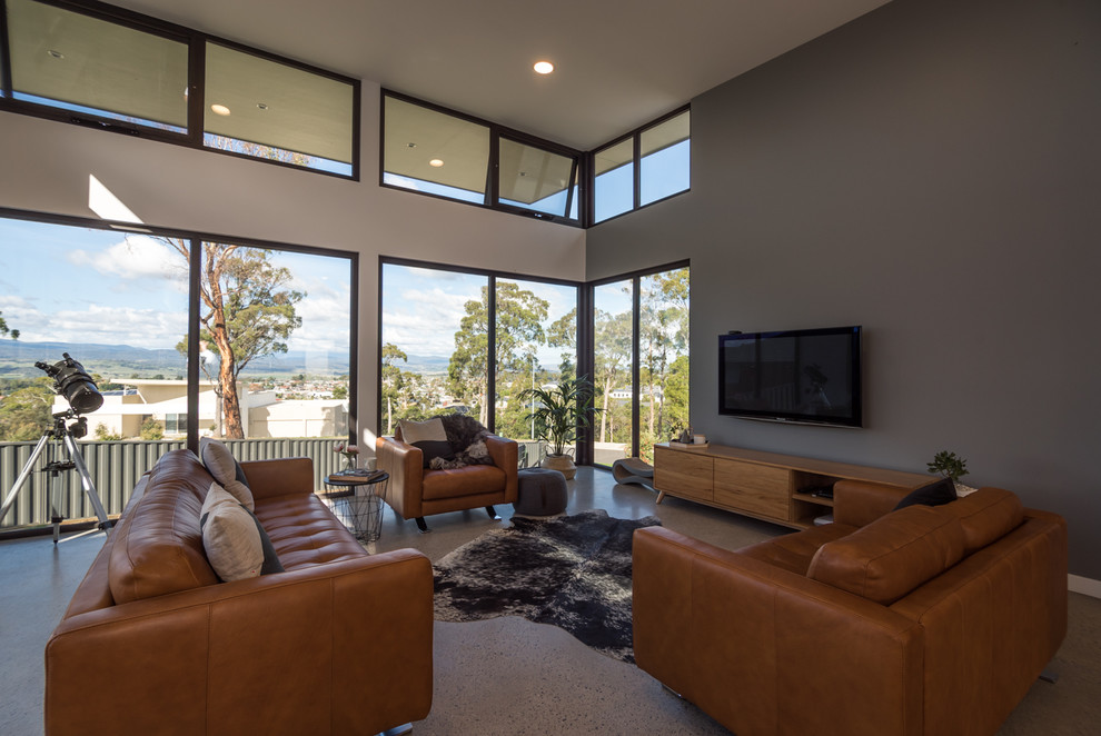 Mittelgroßes, Abgetrenntes Modernes Wohnzimmer mit grauer Wandfarbe, Betonboden und TV-Wand in Hobart