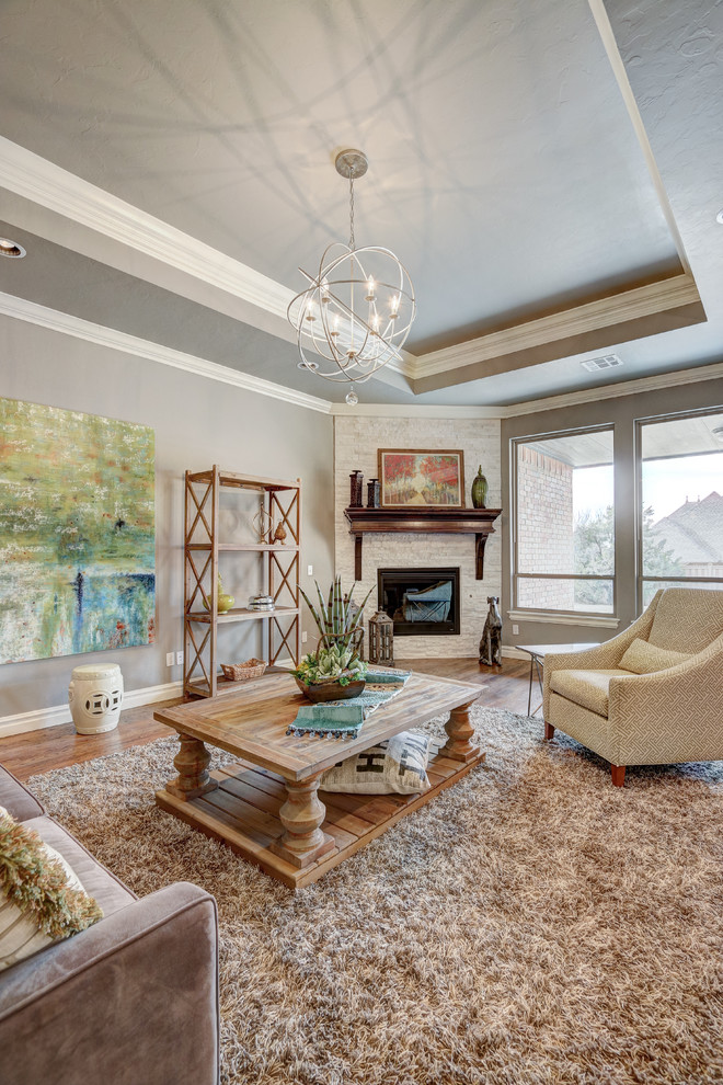 Mid-sized transitional open concept medium tone wood floor living room photo in Oklahoma City with gray walls, a corner fireplace and a stone fireplace