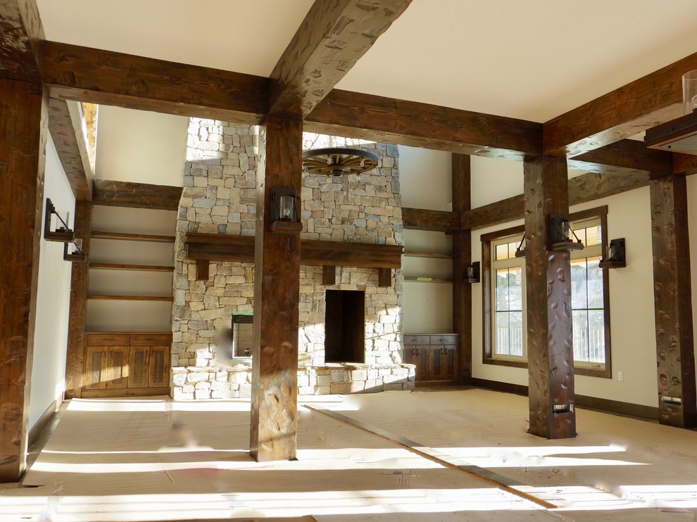 Immagine di un grande soggiorno rustico aperto con sala formale, pareti beige, camino classico, cornice del camino in pietra e nessuna TV