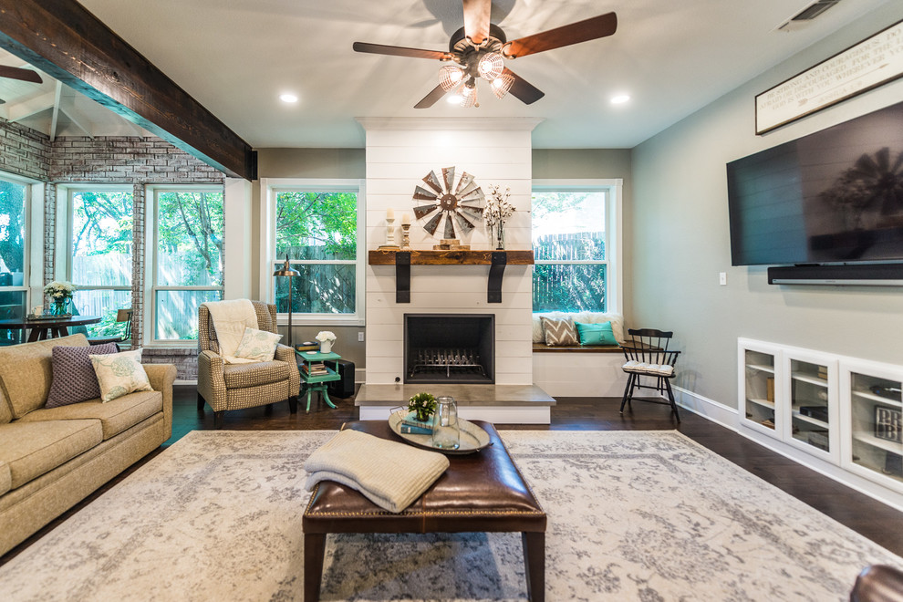 Landhausstil Wohnzimmer mit grauer Wandfarbe, dunklem Holzboden, Kamin, Kaminumrandung aus Holz und TV-Wand in Dallas