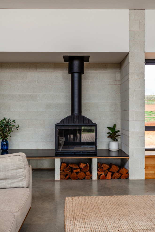 Immagine di un soggiorno design di medie dimensioni e aperto con pavimento in cemento, stufa a legna, TV a parete, pavimento grigio e soffitto a volta