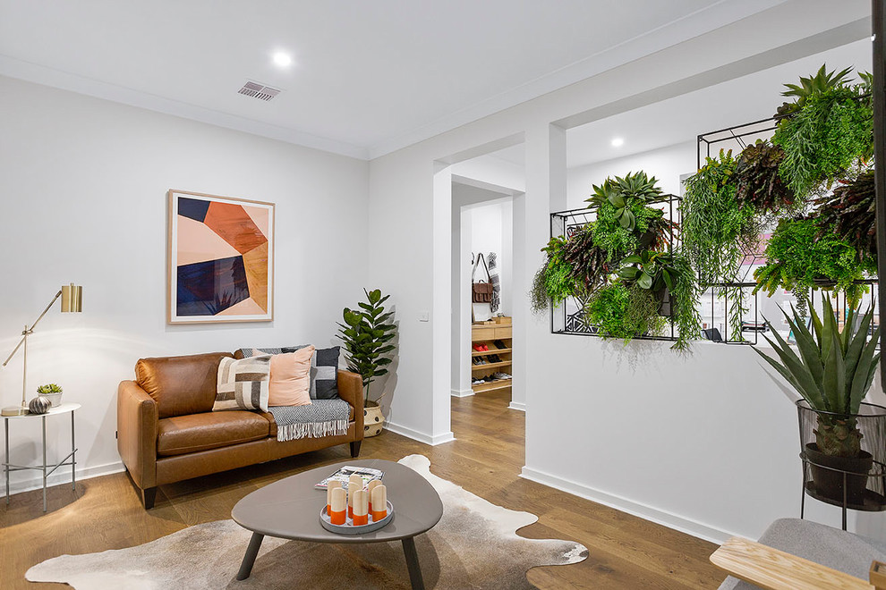 Abgetrenntes Modernes Wohnzimmer mit weißer Wandfarbe, braunem Holzboden und braunem Boden in Melbourne