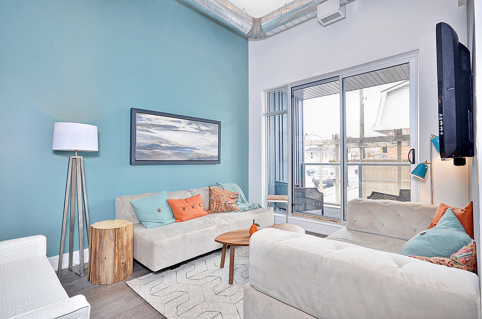 Immagine di un piccolo soggiorno design aperto con pareti blu, pavimento in legno massello medio e TV a parete